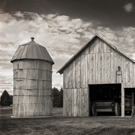 Greyscale image of a rustic barn and silo